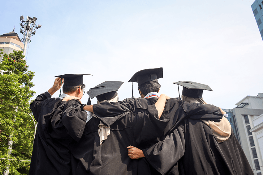 Graduates in caps and gowns with their arms around each other