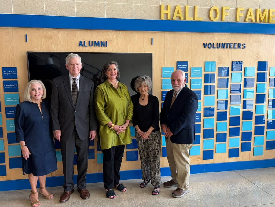 Hall of Fame honorees standing together in front of the alumni wall