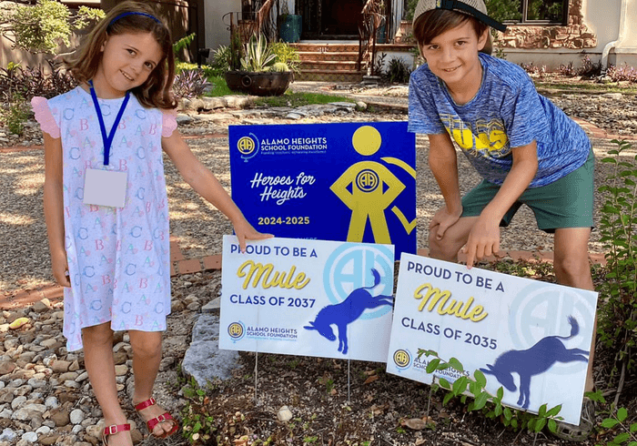 Two Alamo Heights students beside their Heroes for Heights yard signs