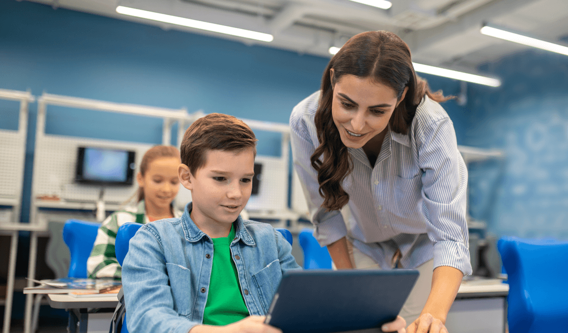 A teacher working alongside students on a tablet in class
